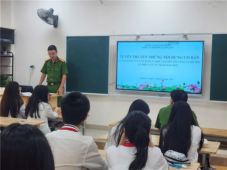 A person standing in front of a classroom with a screenDescription automatically generated