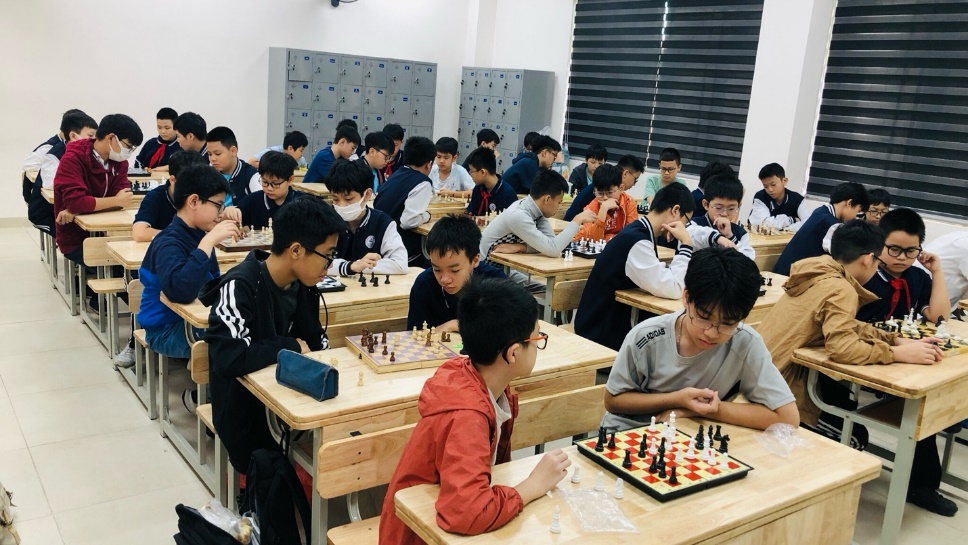 A group of people sitting at desks playing chessDescription automatically generated