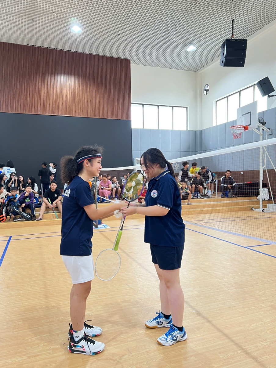 Two people holding tennis rackets in a gymDescription automatically generated