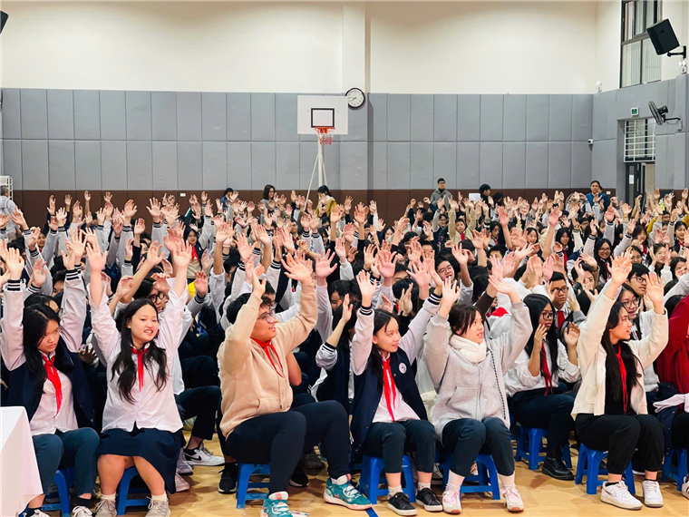 A group of people in a room with their hands upDescription automatically generated