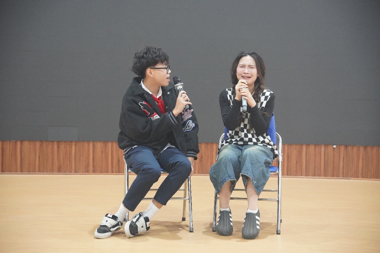 A person and person sitting in chairs holding microphonesDescription automatically generated