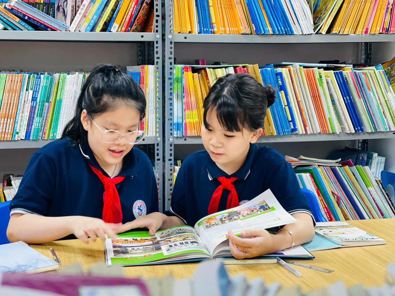 Two girls reading books in a libraryAI-generated content may be incorrect.