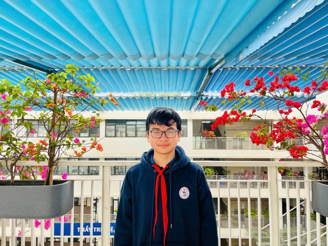 A person standing in front of a white railing with red flowersDescription automatically generated